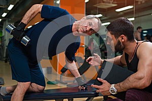 Personal trainer working with senior man in gym