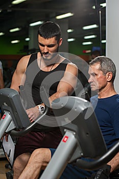 Personal trainer working with senior man in gym