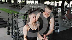 Personal Training Male Trainer Assists Woman in Dumbbell Lift at the Gym