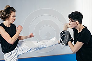 Personal training martial art of taekwondo. Female trainer holding taekwondo kick pad, athlete trainers kicks. Woman kicking