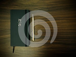 Personalised slimline 2021 New year black diary  and golden pen on wooden background. Top view. photo