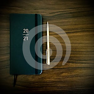 Personalised slimline 2021 New year black diary  and golden pen on wooden background. photo