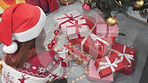 Personifying Christmas elegance, a woman holds a stylishly curled gift with a red ribbon, ready to share the festive