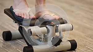 A persons feet are seen actively engaging in a step machine exercise, working to climb up and down the mechanical stairs