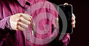 persons hand hold bunch of metal keys and blocked smartphone, security concept b