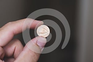 Persons hand holding out a fils coin, less than a dirham, the Currency of the United Arab Emirates -  on a brown background. Money