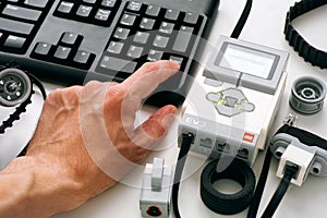 Persons hand on keyboard coding LEGO MINDSTORMS EV3 robot blocks on computer
