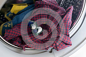 persons hand put special cleaning pod or capsule in the washing machine with dirty cloth