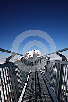 Perspctive view on Steel hanging bridge between ice mountain peak middle blue clear sky background and white cloudy on winter