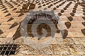 Perspective from below of the bas-relief moldings of the rock shells and wrought iron balcony and window with elongated shadows