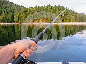 Perspective from a boat of a man hand holding a fishing rod jigging for fish photo