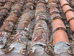 perspective close up of red old repaired terracotta roof tiles with damage and texture