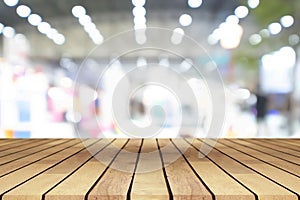 Perspective empty wooden table over blurred shopping mall background, for product display montage or design layout.