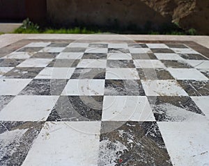 Perspective image of floor with black and white tiles. Chess board made of stone. Old picture