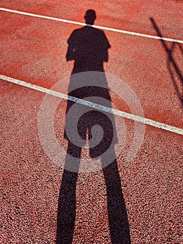 Perspective shadow of tennis player on tennis court. Long Shadow of Tennis Player Backgrounds. Racket sports