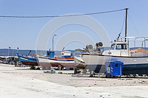 Perspective shot of back side fishing boats on ground for painting of trunk at Lesvos, Kalloni