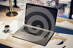 Perspective top view on dark modern laptop monitor with place for your logo or text on light wooden table with coffee mug and