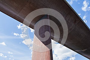 Perspective from under a huge, concrete bridge against summer sky