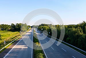 Perspective view of autobahn in with trees and clear blue sky background