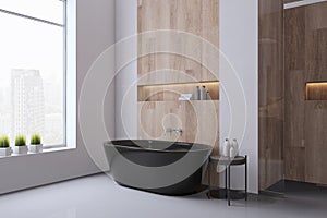 Perspective view of bathroom interior design with tiles grey floor, black bath, wooden walls and window with city view. 3D