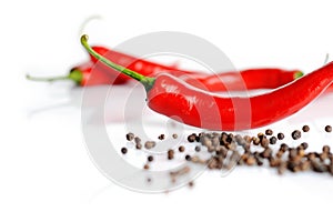 Perspective view of chilli pepper and black pepper on white