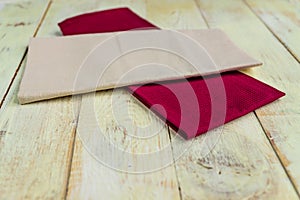 Perspective view of cloth napkins of beige and burgundy colors on rustic white wooden table. Shallow depth of field
