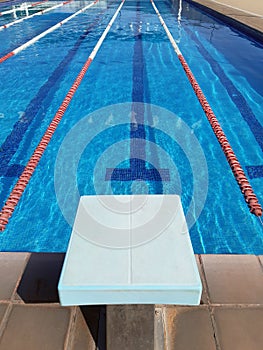 Perspective view of competition pool lanes with floating lanes and start block. Water sport, swimming and competition concept