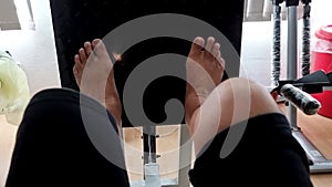 Perspective view of elderly physiotherapy patient performing leg press to strengthen weakened thigh muscles as recovery