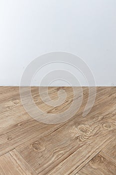 Perspective view of empty interior room with white cement wall and brown wooden herringbone floor