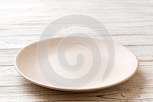 Perspective view of empty light plate on wooden background. Empty space for your design