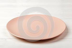 Perspective view. Empty pink matte plate on white wooden background