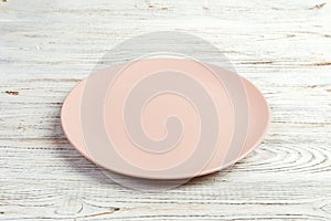 Perspective view. Empty pink matte plate on white wooden background