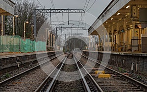 Perspective view on empty railway tracks and electric infrastructure equipment, wires at Acton central rail station