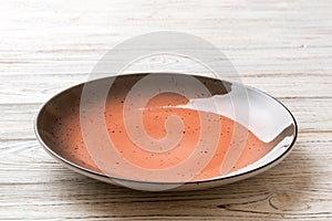 Perspective view of empty red plate on wooden background. Empty space for your design