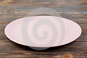 Perspective view. Empty rose matte plate on dark wooden background