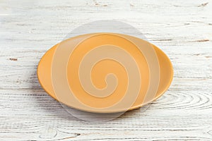 Perspective view. Empty yellow matte plate on white wooden background