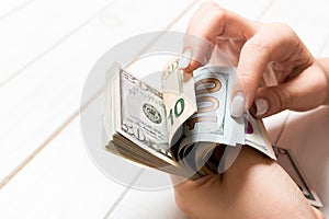 Perspective view of female hands counting money. One hundred and other dollar banknotes on colorful background. Business concept