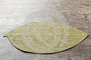 Perspective view of leaf shaped tablecloth for food on cement background. Empty space for your design.