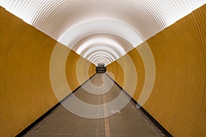 Perspective view of long modern futuristic yellow underground pedestrian tunnel in Stockholm Sweden.