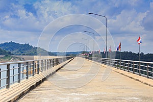 Perspective view of a long road dam, with Thai national flags.