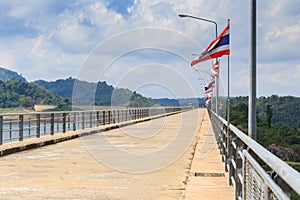 Perspective view of a long road dam, with Thai national flags.