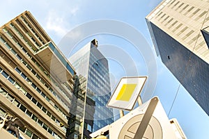 Perspective view of modern high-rise glass skyscraper building and main road traffic sign