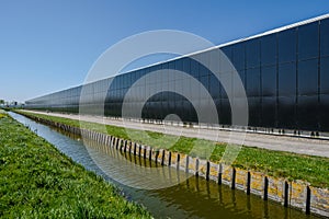 Perspective view of a modern industrial greenhouse with solar panels at the side in the Netherlands