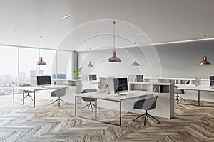 Perspective view on stylish sunlit open space office with light furniture, modern computers, dark chairs on wooden parquet floor