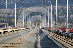 Perspective view on tarmac road on river bridge with lamp posts
