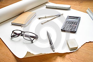 Perspective view on technical drawing setup, with pencil, compass, ruler, calculator, glasses, eraser and notebook