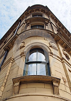 perspective view of a 19th century tall stone neoclassical building with ornate curved windows in the little germany business