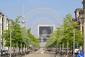 Perspective view of tree-lined street and park in Berlin with clouds in clear blue sky background