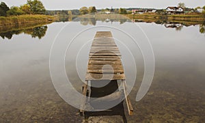 Perspective view of wooden pier at lake. Damaged Empty wooden bridge or table top with the rural lake and sky landscape