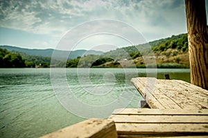 Perspective Wooden board empty table in front of blurred nature background with mountain and lake.